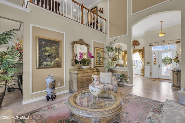 interior space with light tile patterned floors, crown molding, and a high ceiling