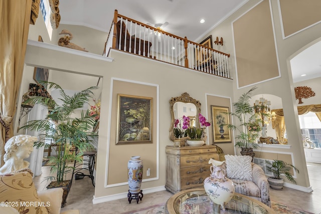 sitting room with a towering ceiling and ornamental molding