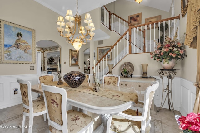 dining area featuring crown molding, a towering ceiling, light tile patterned flooring, and a notable chandelier