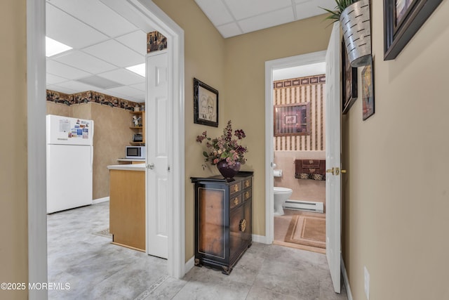 hallway with a baseboard radiator and a drop ceiling