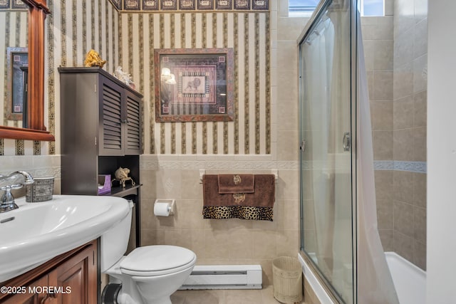 full bathroom with bath / shower combo with glass door, tile walls, vanity, baseboard heating, and toilet