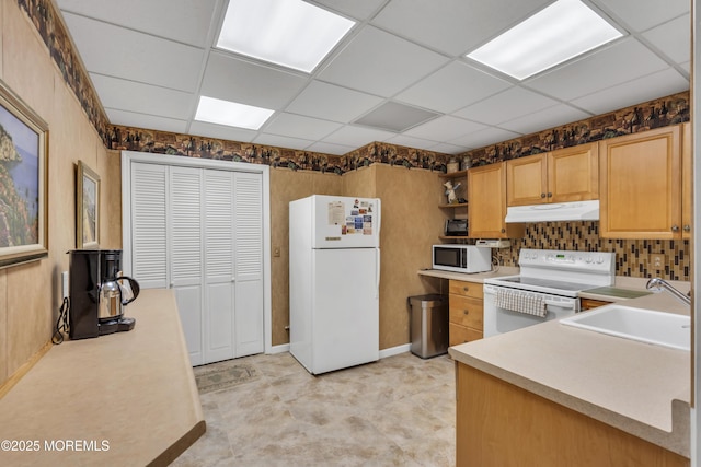 kitchen featuring a drop ceiling, sink, and white appliances