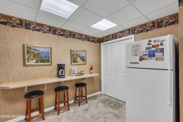 kitchen with a paneled ceiling, a kitchen breakfast bar, kitchen peninsula, and white fridge