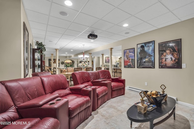 home theater featuring baseboard heating, a paneled ceiling, and decorative columns