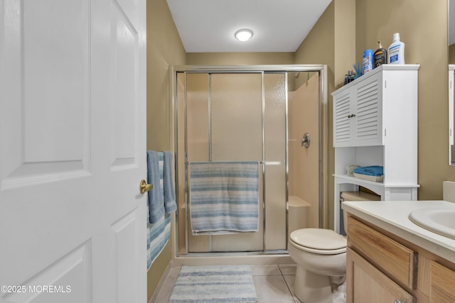 bathroom featuring tile patterned flooring, vanity, toilet, and walk in shower