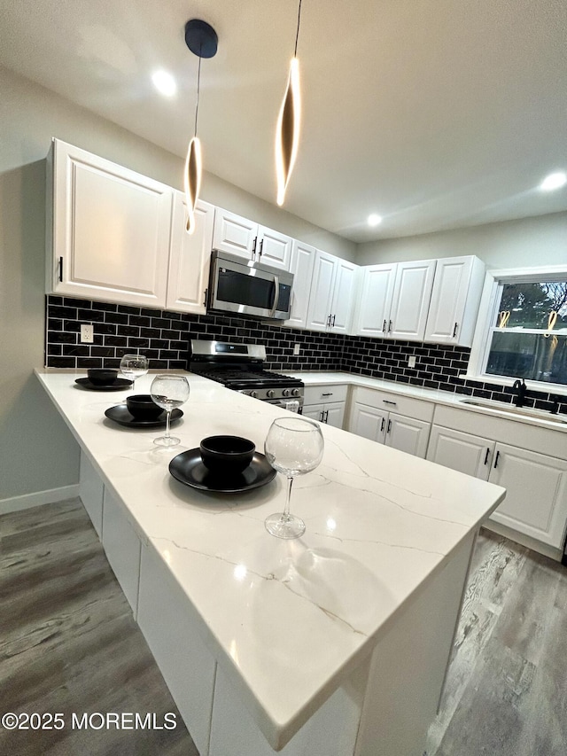 kitchen featuring decorative light fixtures, stainless steel appliances, and white cabinets