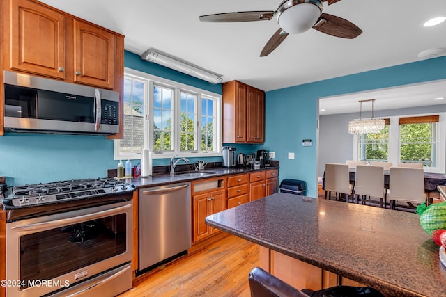 kitchen featuring pendant lighting, sink, a breakfast bar, appliances with stainless steel finishes, and light hardwood / wood-style floors