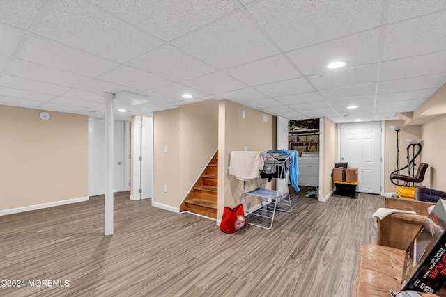 interior space with wood-type flooring, washer / clothes dryer, and a drop ceiling