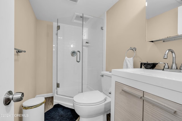 bathroom with an enclosed shower, vanity, and toilet