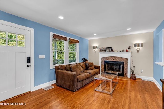 living room featuring a tile fireplace and light wood-type flooring