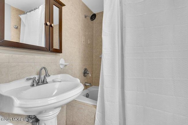 bathroom featuring shower / bathtub combination with curtain, sink, and backsplash