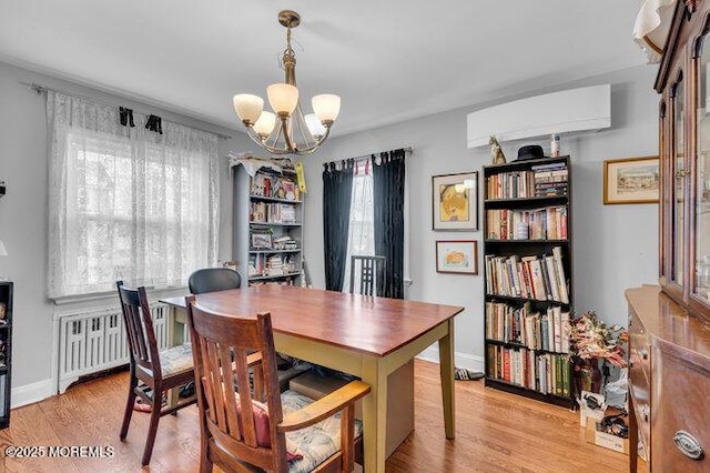 dining room with radiator, a wall mounted AC, a chandelier, and light wood-type flooring