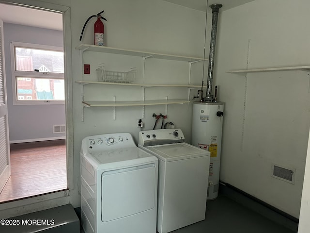 washroom with water heater and washer and clothes dryer