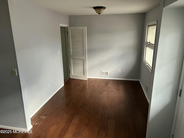 unfurnished room with dark wood-type flooring