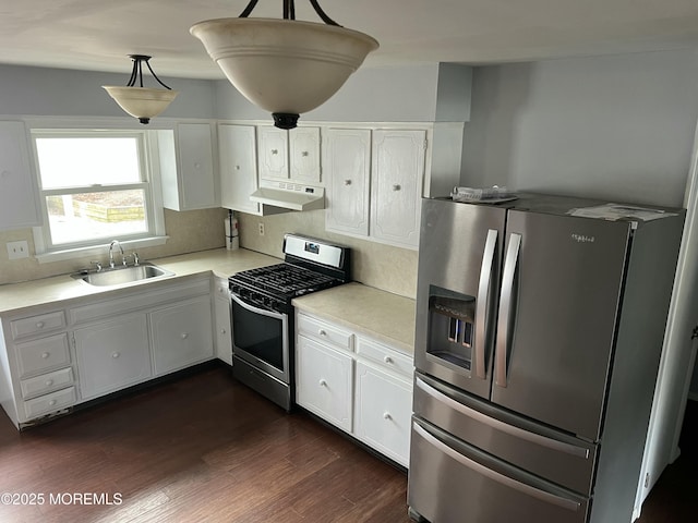 kitchen featuring dark wood-type flooring, sink, hanging light fixtures, appliances with stainless steel finishes, and white cabinets