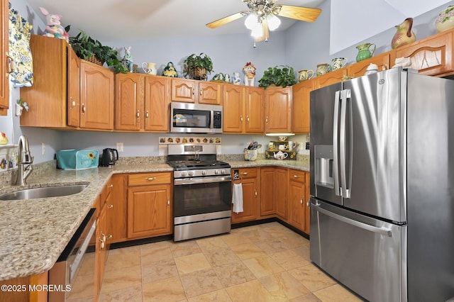 kitchen featuring light stone counters, ceiling fan, stainless steel appliances, and sink