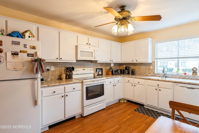 kitchen with sink, white cabinetry, tasteful backsplash, white appliances, and light hardwood / wood-style floors