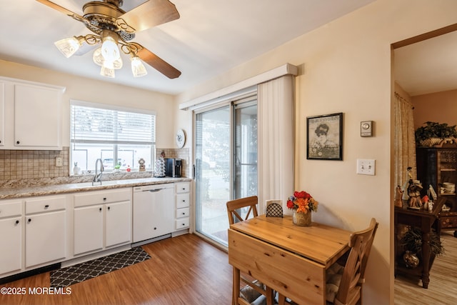 kitchen with white cabinetry, white dishwasher, light hardwood / wood-style floors, and tasteful backsplash