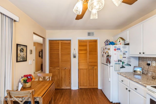 kitchen with white cabinetry, decorative backsplash, hardwood / wood-style flooring, white fridge, and light stone counters