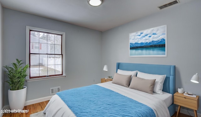 bedroom featuring visible vents, baseboards, and wood finished floors