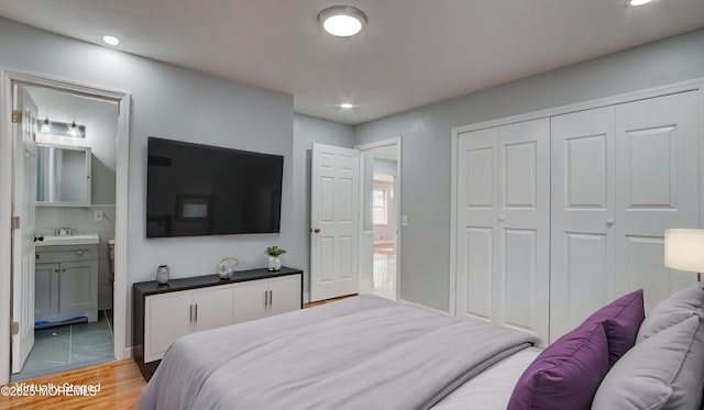 bedroom featuring recessed lighting, ensuite bathroom, light wood-style floors, a closet, and a sink