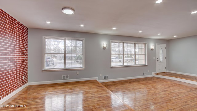 interior space featuring light wood-type flooring, plenty of natural light, and brick wall