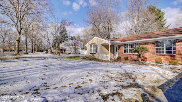 snow covered property featuring brick siding