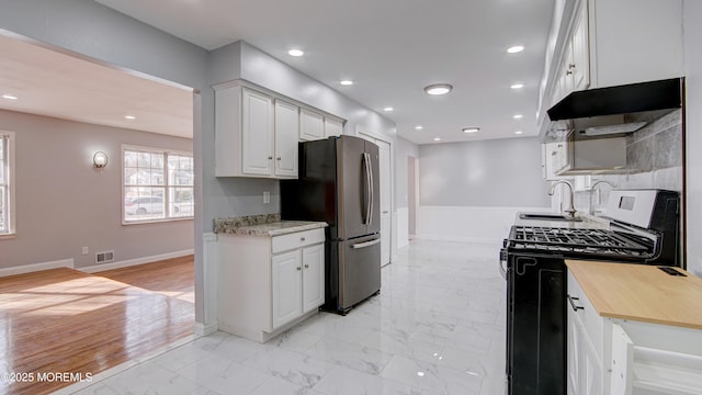 kitchen featuring visible vents, marble finish floor, a sink, stainless steel appliances, and white cabinets