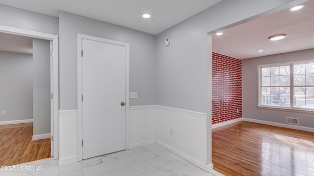 entrance foyer featuring visible vents, baseboards, a wainscoted wall, recessed lighting, and marble finish floor