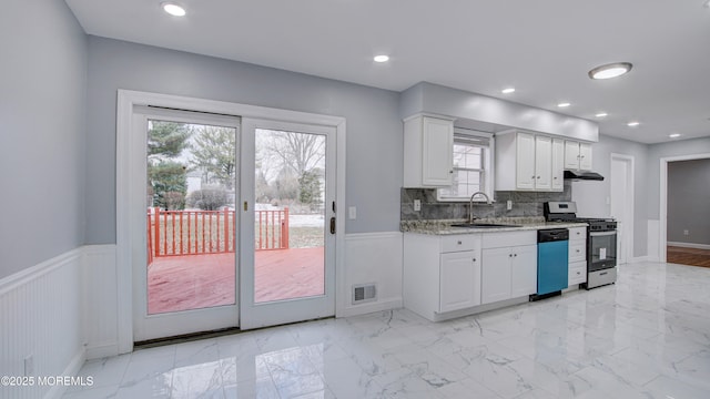 kitchen with visible vents, under cabinet range hood, a wainscoted wall, gas range, and white cabinets