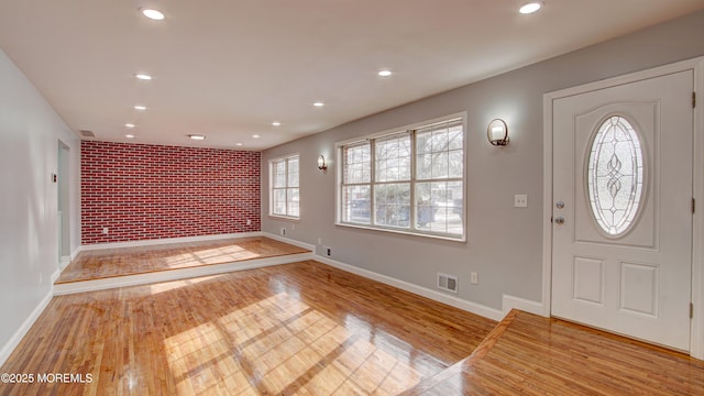 foyer featuring brick wall and light wood-type flooring