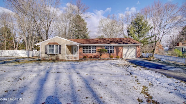 ranch-style house with a garage, brick siding, driveway, and fence