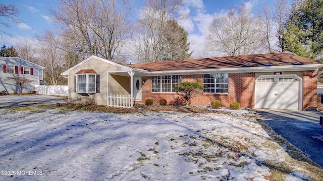 ranch-style house with a garage, fence, brick siding, and aphalt driveway