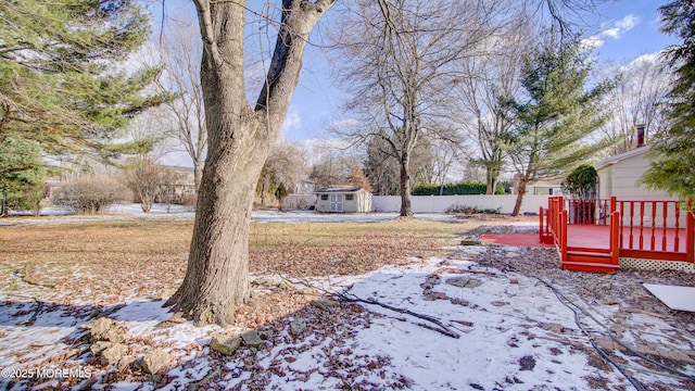 snowy yard with a wooden deck and a shed