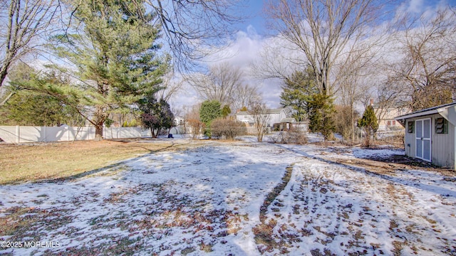 snowy yard with a storage shed, an outdoor structure, and fence