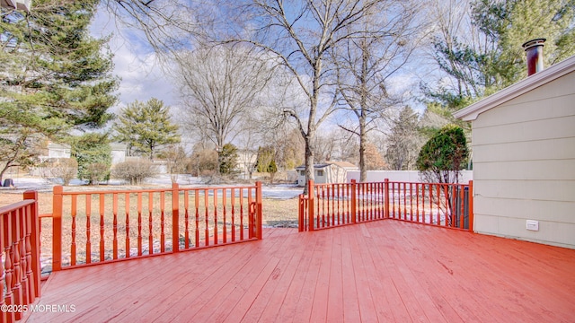 wooden terrace featuring a storage shed, an outbuilding, and fence