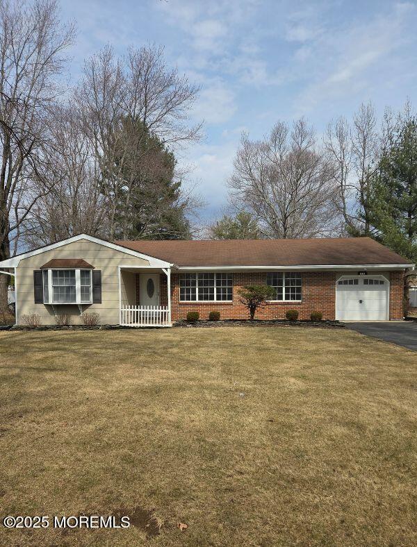 ranch-style house with a front yard, brick siding, a garage, and aphalt driveway