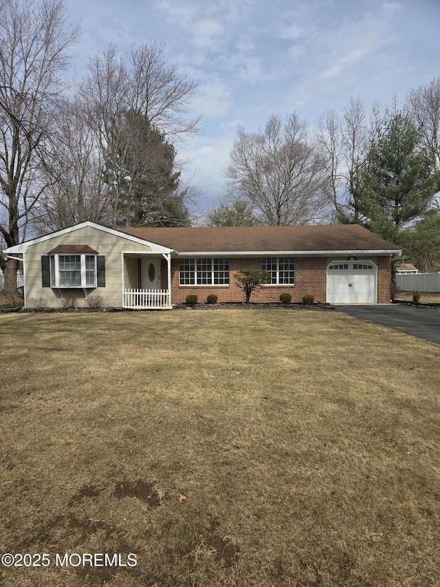 single story home with brick siding, aphalt driveway, a front lawn, and an attached garage