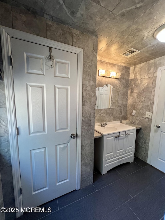 bathroom with vanity and tile walls