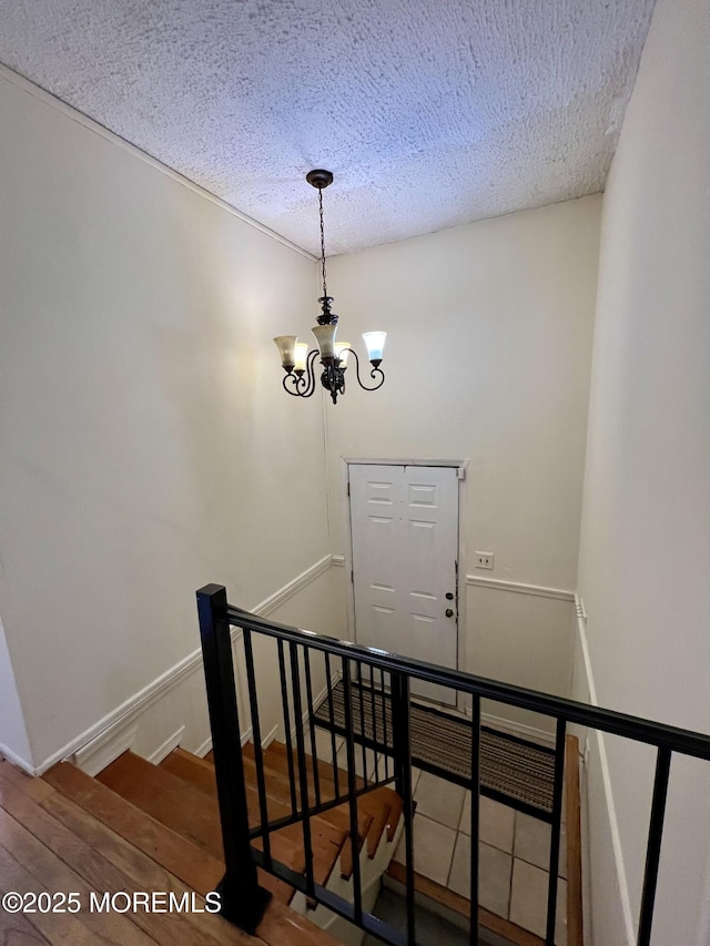 stairway featuring an inviting chandelier, a textured ceiling, and hardwood / wood-style flooring