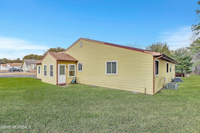 back of property featuring cooling unit and a lawn