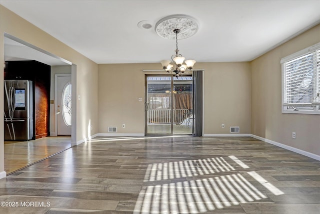 unfurnished dining area featuring wood-type flooring and an inviting chandelier