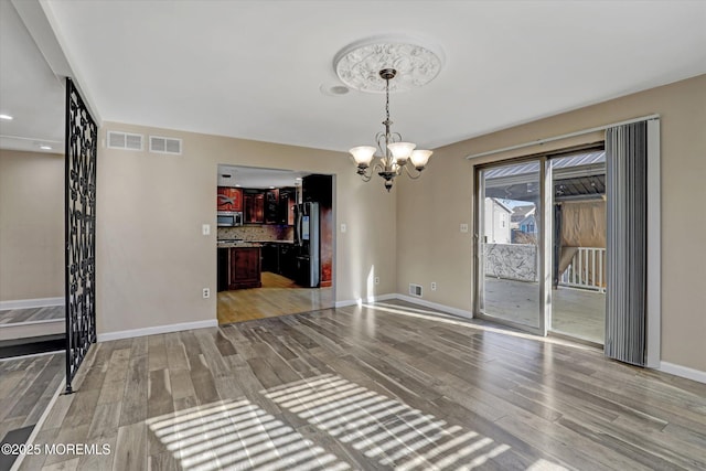 unfurnished dining area with light wood-type flooring and an inviting chandelier