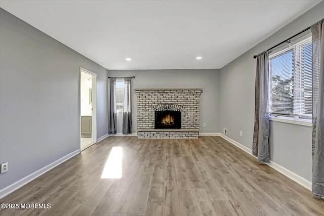 unfurnished living room featuring a fireplace, light hardwood / wood-style floors, and a wealth of natural light