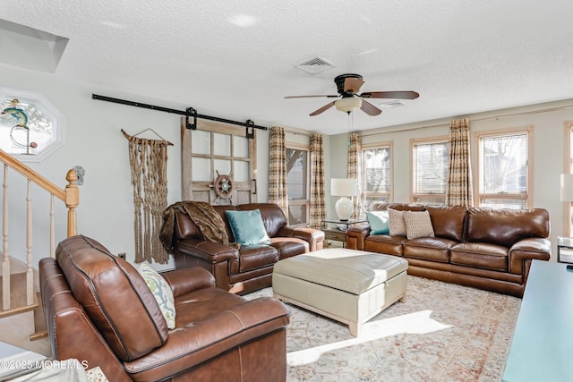 living room featuring a barn door, a textured ceiling, and ceiling fan