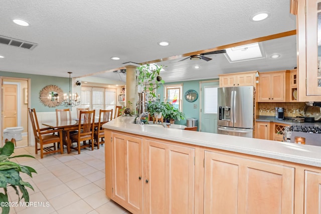 kitchen with light tile patterned floors, hanging light fixtures, stainless steel fridge with ice dispenser, decorative backsplash, and light brown cabinets