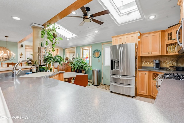 kitchen with sink, lofted ceiling with skylight, stainless steel fridge with ice dispenser, decorative light fixtures, and light brown cabinets