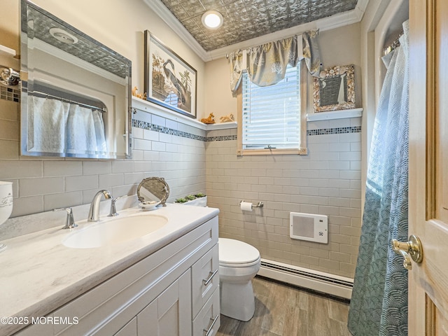 bathroom with crown molding, a baseboard radiator, vanity, and tile walls