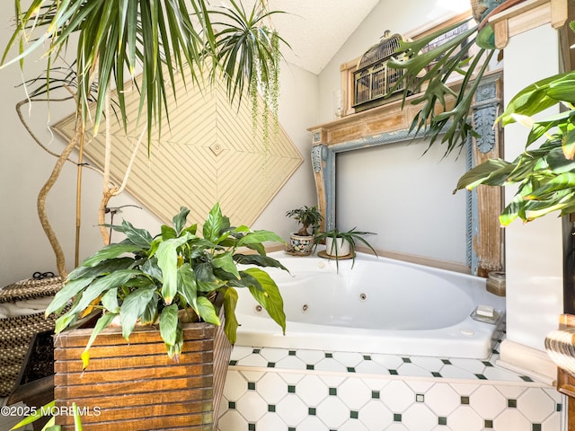 bathroom with vaulted ceiling, a textured ceiling, and tiled tub