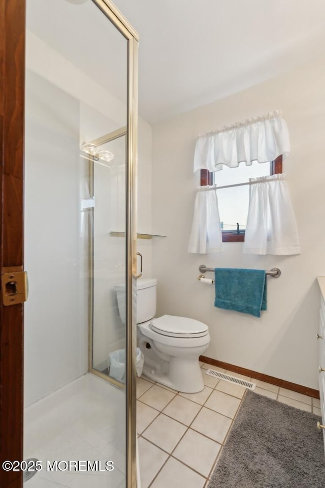 bathroom featuring tile patterned floors, toilet, a shower with door, and vanity